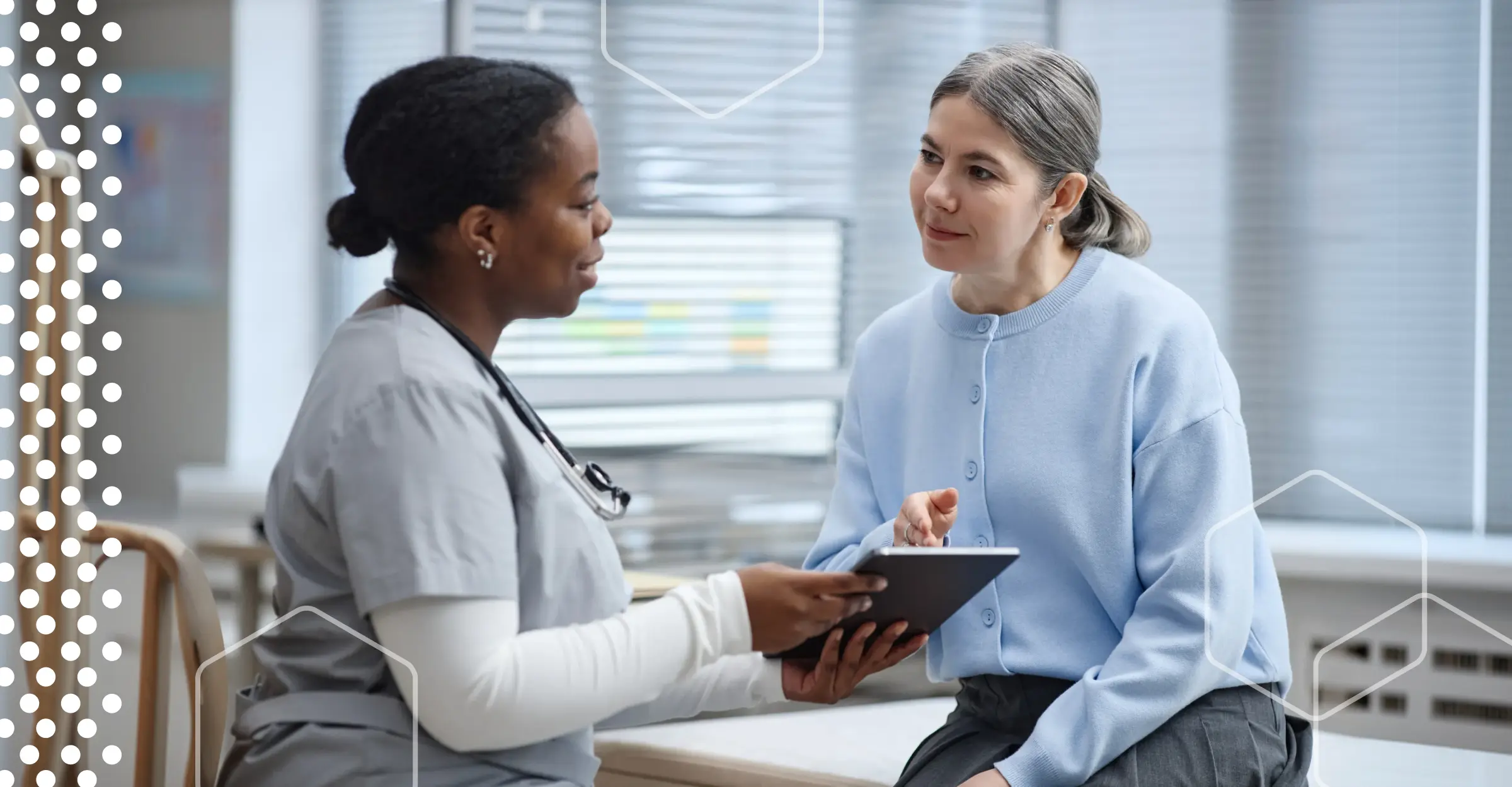 Healthcare provider showing a tablet to a patient in an exam room