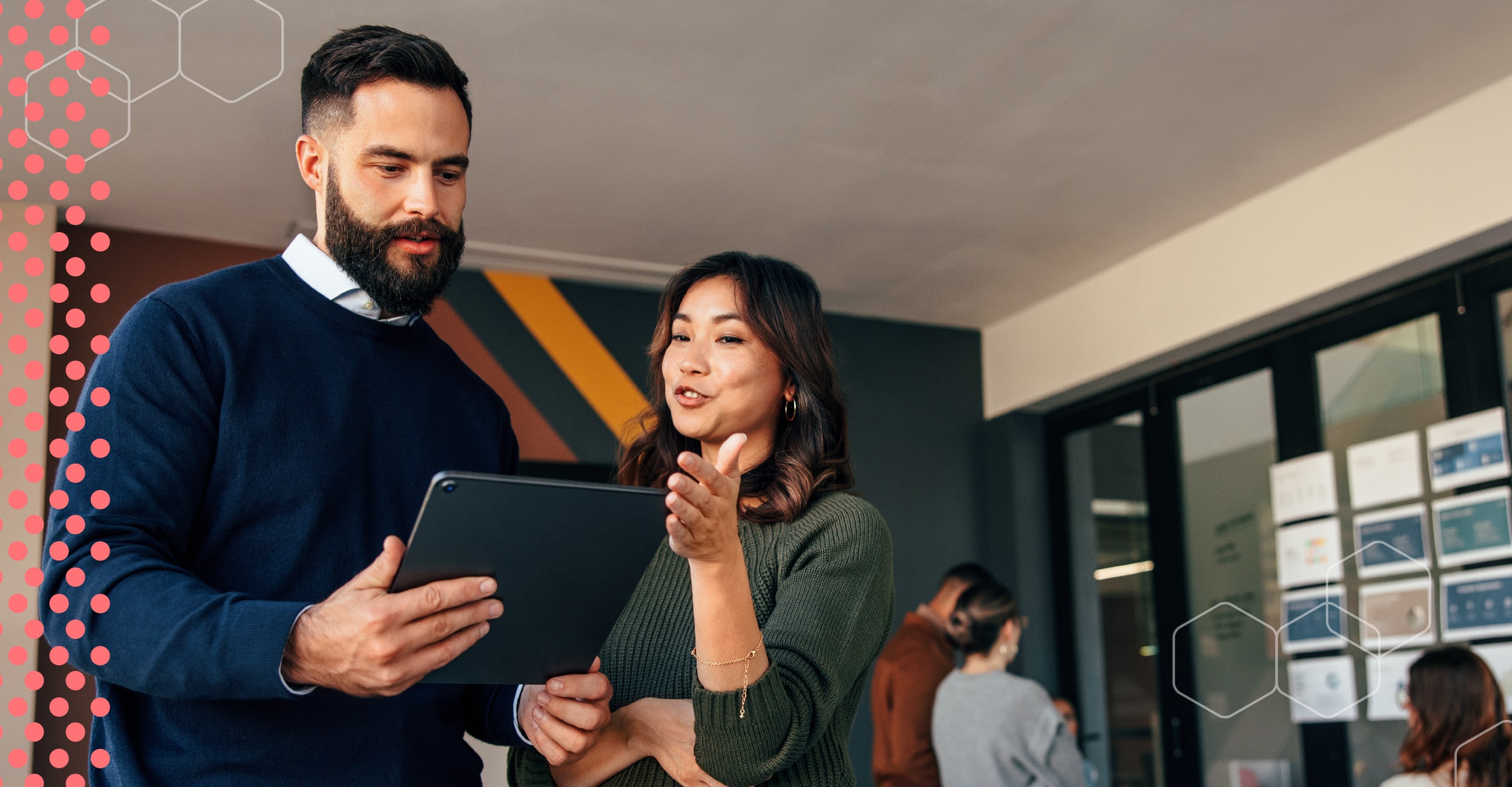 A woman and man in an office looking at a mobile tablet.