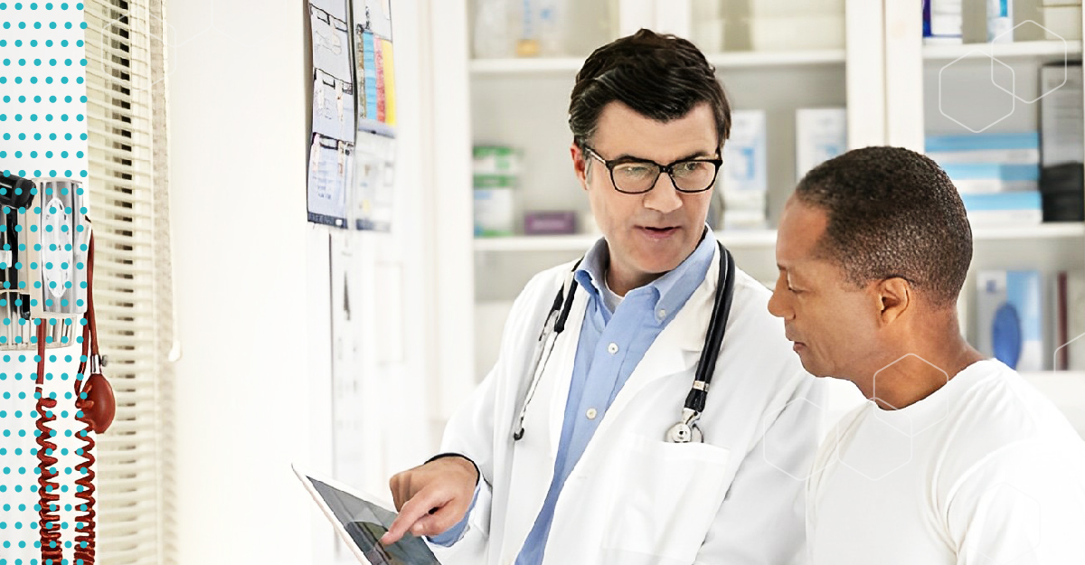 A man doctor speaks to a patient, who is a man of color.