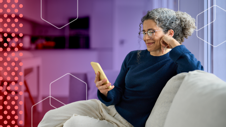 Older woman looks at her phone while sitting on a couch